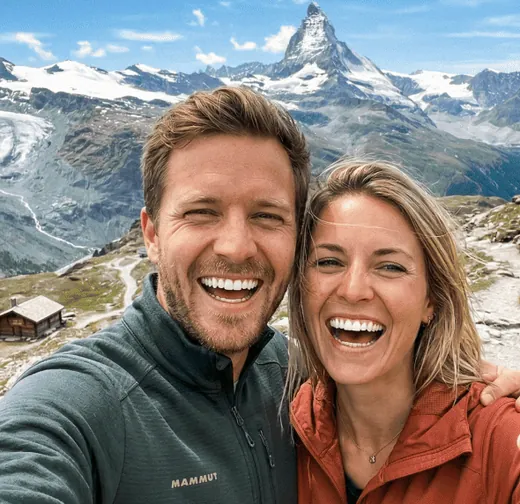 Lachendes Paar beim Wandern vor schneebedeckten Bergen